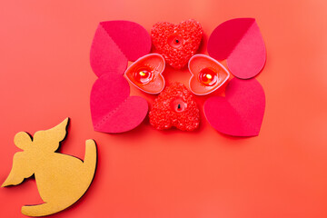 Red background with an angel, scented candles and paper heart. Valentines Day.