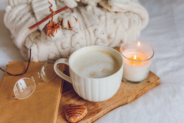 Home cozy decor. A mug of cappuccino, cookies, a candle on the bed. Winter morning.