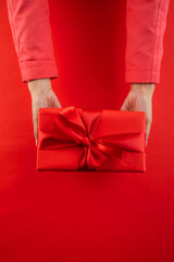 female hands delivering a valentine's day gift on red background