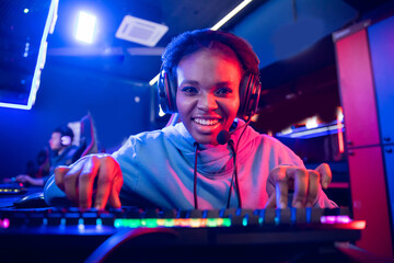 Portrait Streamer African young woman professional gamer playing online games computer, neon color © Parilov