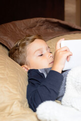 Small kid using digital tablet in the bedroom.