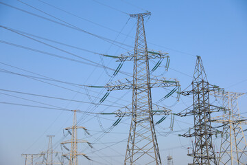 High voltage towers against blue sky on sunny day