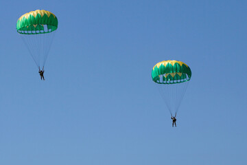 Military army parachutes paratroopers jump in blue sky from airplane ceremony day. Armed Forces special battalion staff exercise. National defense concept, security.
