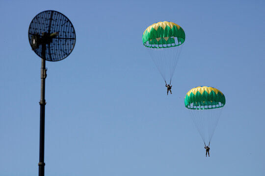 Military army parachutes paratroopers jump in blue sky from airplane ceremony day. Armed Forces special battalion staff exercise. National defense concept, security.