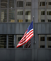 American flag hanging on a dark building with reflections.