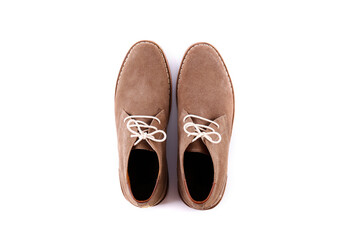 A pair of light brown suede chukka boots isolated on white background. Men's casual dress shoes with white laces laces. Top view, copy space for text, flat lay.