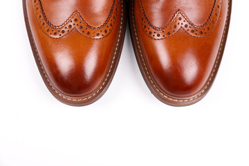 Cropped shot of a pair of light brown double monk strap shoes isolated on white background. Versatile business casual dress shoes without laces. Top view, copy space for text, flat lay.