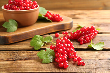 Delicious red currants and leaves on wooden table