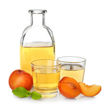 Delicious plum liquor, ripe fruits and mint on white background. Homemade strong alcoholic beverage