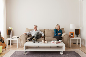 Angry senior couple sitting on sofa