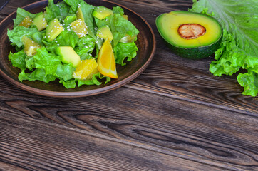 fresh summer homemade salad of vegetables and fruits, orange, lettuce, avocado and sesame seeds, healthy food, organic, vegetarian eco health and immunity products