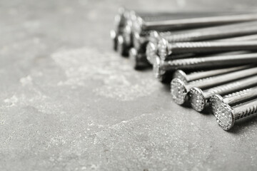 Many metal nails on grey background, closeup. Space for text