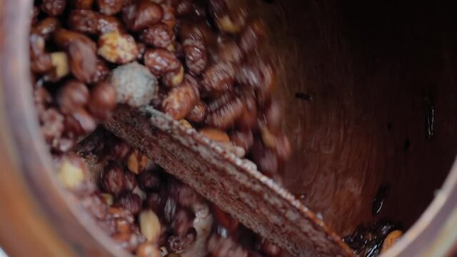 Slow motion: professional nut roaster machine for mixing, roasting and glazing peanuts: close up. Production, manufacturing, preparation, technology and street food concept