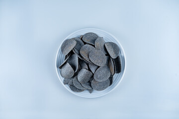 Black potato chips with salt on a gray background