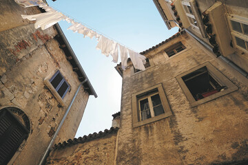 Fototapeta na wymiar Weiße Wäsche auf einer Wäscheleine in mediterranem Innenhof unter blauem Himmel