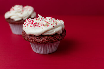 red velvet cupcakes on red background with cream and sprinkles 