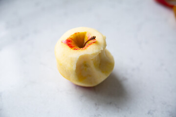 Peeled bitten apple on a kitchen marble countertop.