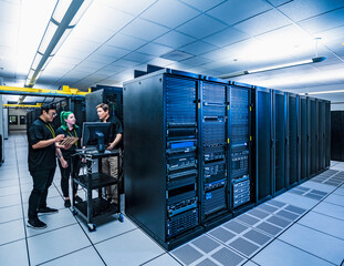 Co-workers with computer in data center server room