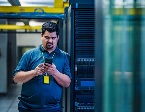 Employee looking at smart phone in data center
