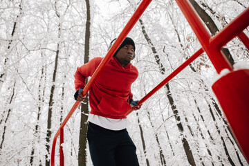 Young african american man doing exercise on winter day in forest