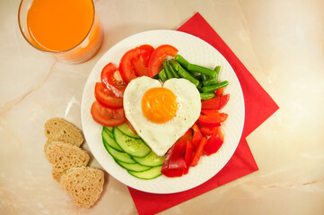healthy breakfast with egg, bread, tomatoes, cucumber slice, bell pepper, green beans and a glass of juice for Valentine's day morning 