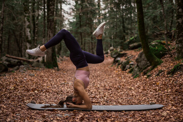 Sports woman practicing headstand yoga pose in forest at Ordesa National Park, Huesca, Spain