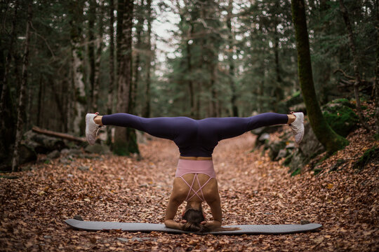 Sportswoman stretching while doing headstand in forest at Ordesa National Park, Huesca, Spain