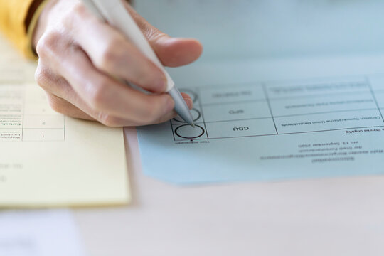 Close-up of woman filling voting ballot at home