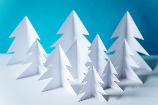 Paper forest with white trees on table against blue background
