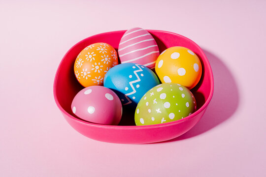 Variation design on colorful Easter eggs in red bowl on purple background