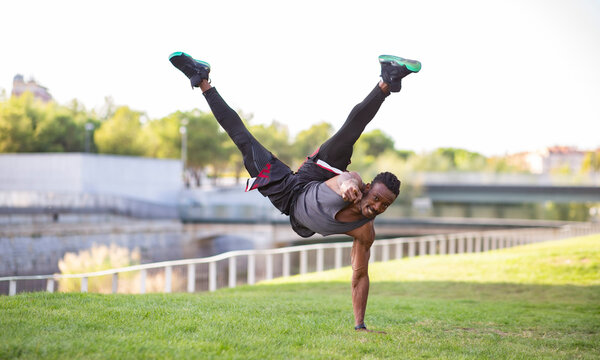 Smiling athlete pointing while doing handstand outdoors