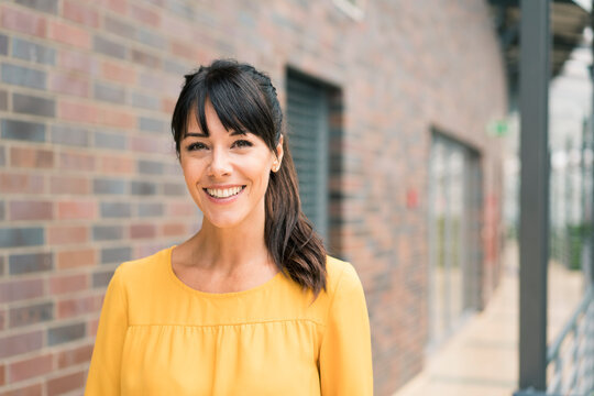 Smiling female entrepreneur by wall in corridor