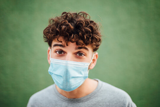 Young man with surgical mask against green background