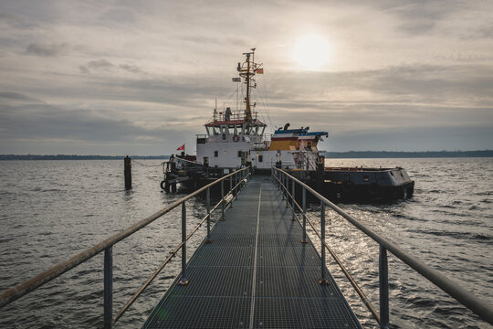 Sun rising over fishing boat moored at edge of coastal jetty