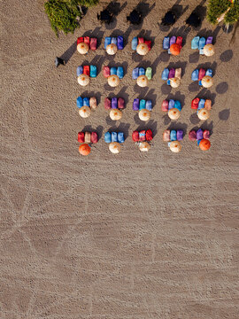 Aerial view of rows of umbrellas and deck chairs on empty Kuta Beach, Bali, Indonesia