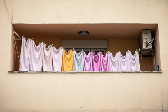 Row of colorful sheets on clothesline on balcony