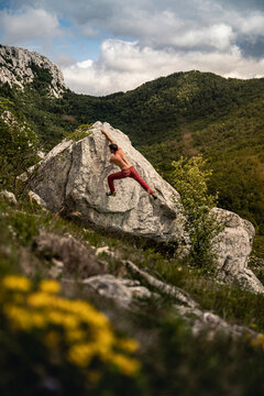 Boulderer climbing rock in mountain landscape