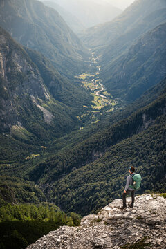 Woman with backpack standing on rock and looking at valley
