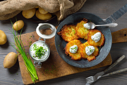 Resche bayerische Kartoffelpuffer mit Schnittlauchquark in der Eisenpfanne serviert &ndash; Crunchy Bavarian potato pancakes with sour cream and fresh chives 
