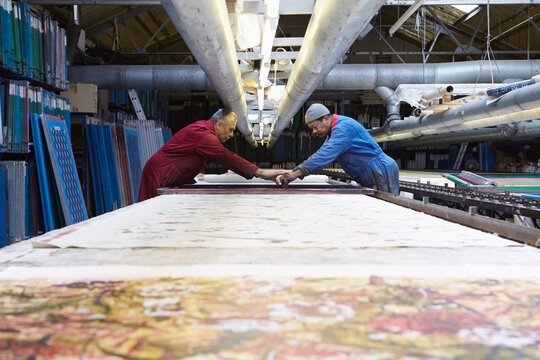 Two men printing fabric in factory