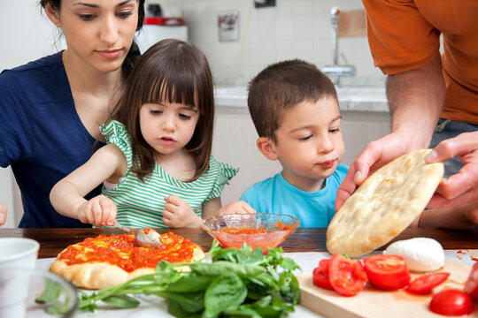 Family making homemade pizza