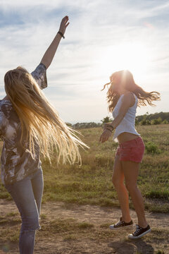 Two young women dancing in field