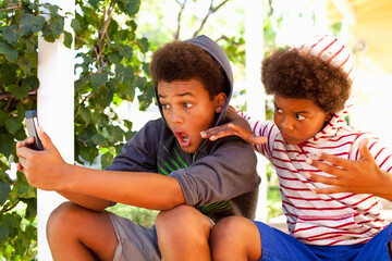 Two brothers taking selfie on smartphone in garden