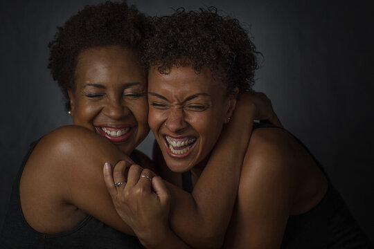 Studio portrait of two mature women hugging and laughing