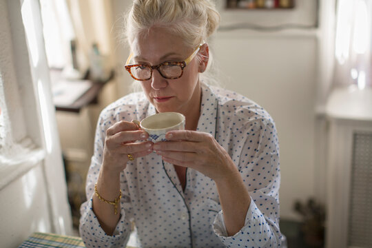 Sad mature woman sitting at breakfast table with teacup