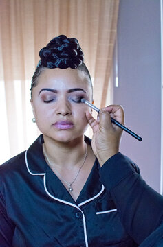 Bride having eyeshadow applied in hotel room