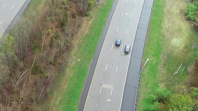 Aerial Close Up View of a Tesla Vehicle Autonomously Switching Lanes to Pass A Slower Car