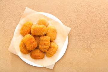 Plate with tasty nuggets on color background