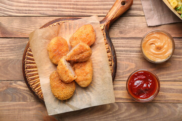 Board with tasty nuggets on wooden background