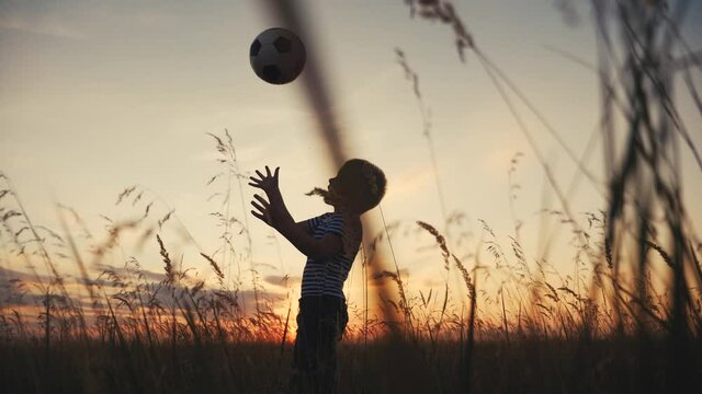 Childhood dream. boy play soccer ball in the park silhouette. happy family kid fun dream concept. kid boy play on the field silhouette at sunset carries a soccer ball. baby winner